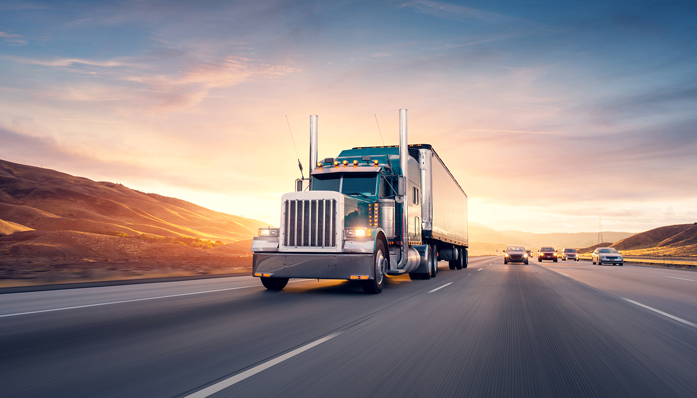 Semi driving on the highway, the sun setting in the background